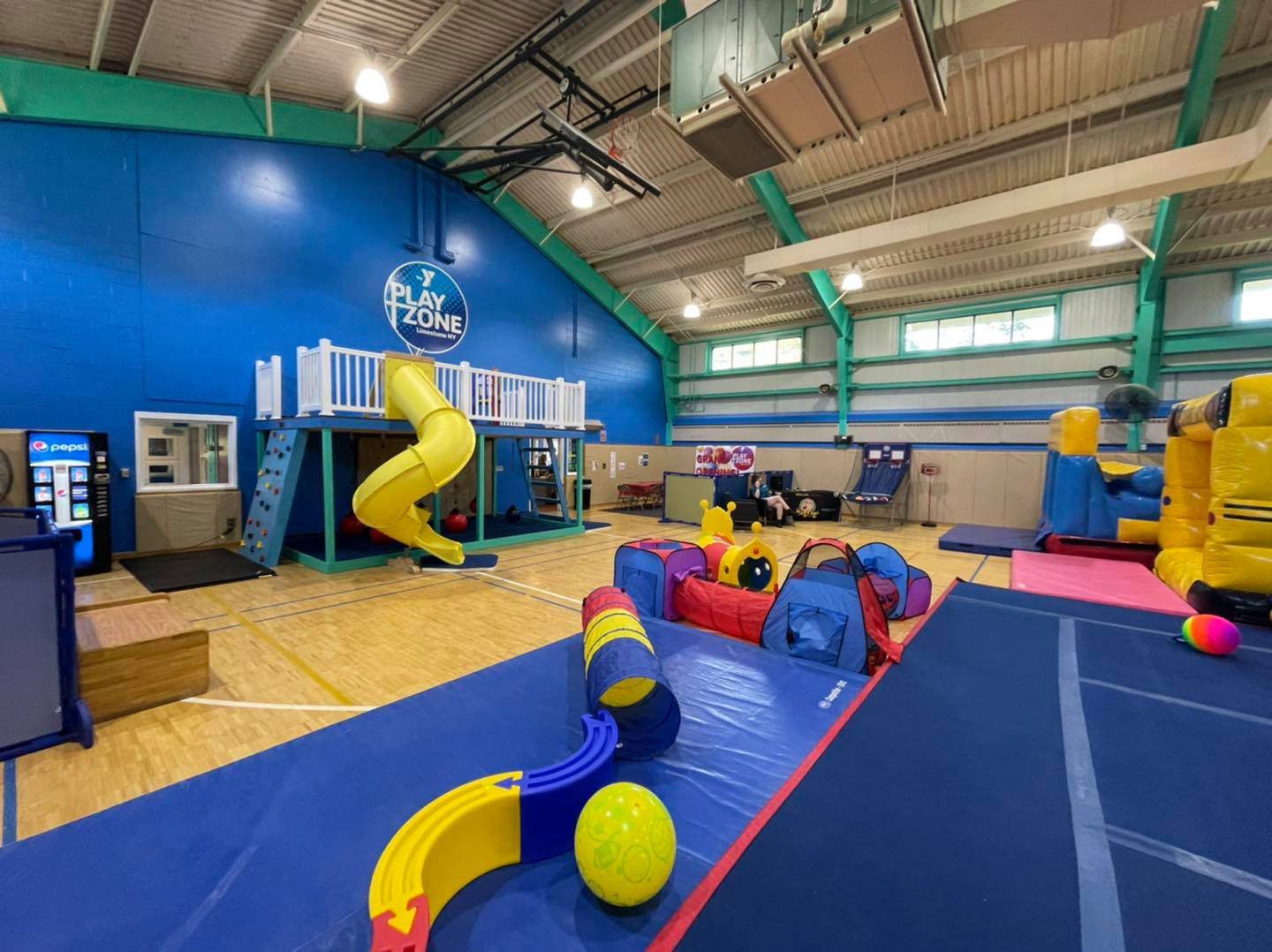 Photo shows indoor play area with mats, balls, a circular slide, and more