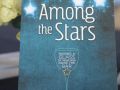 Photo shows program book of Among the Stars in front of floral arrangement